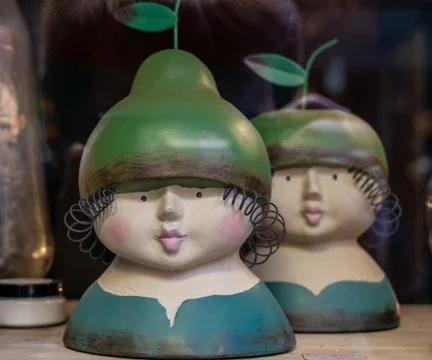 Two ceramic doll heads with a green pear-shaped hat on their heads Stock Photos