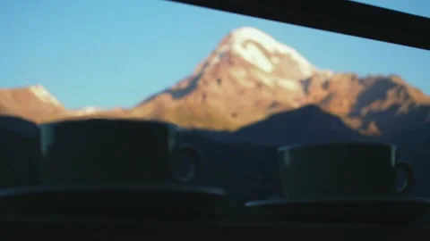 Two ceramic mugs with hot drinks on the background of mountain range on a dawn Stock Footage 248528489