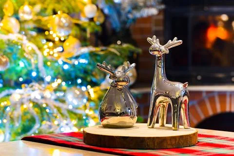 Two ceramic reindeer, silver and glossy, stand on a maple wood slice. In th.. Stock Photos