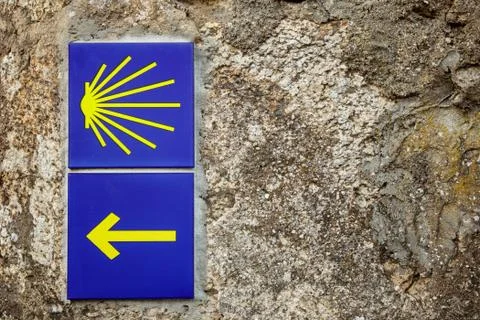 Two ceramic tiles on a stone wall point the way on the Camino De Santiago Stock Photos
