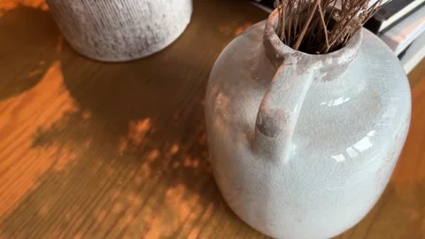 Two Ceramic Vases with Dry Leaves on Warm Wood Table Stock Footage 332259939