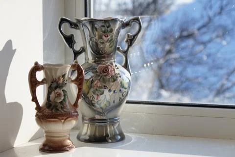 Two ceramic vases stand on a windowsill with beautiful sunlight. Stock-Fotos