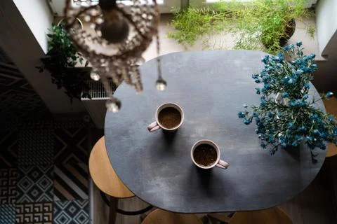 Two ceramic white cups of coffee standing on a wooden oval table Foto stock