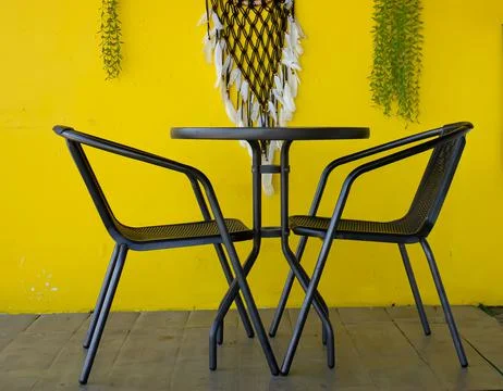 Two chairs and a table in black on a yellow background Stock Photos