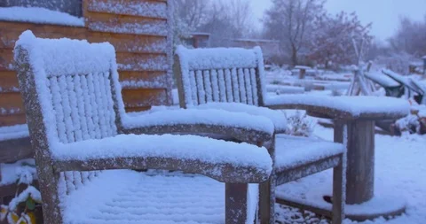 Two chairs covered in snow as it continues to fall. Slow motion. Video stock 102405908