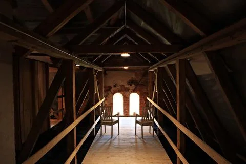 Two chairs in front of the windows among the timber joists in the attic of an Stock-Fotos