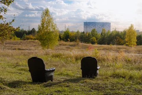 Two chairs on meadow with forest view and large building Stock Photos
