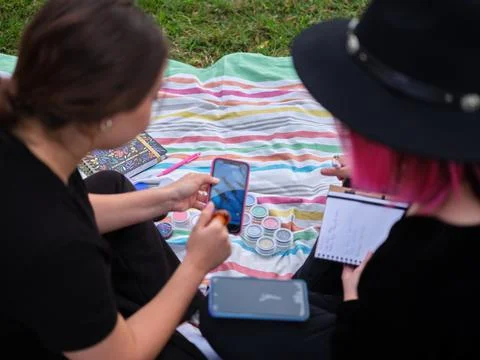 Two character make-up students looking at designs on the phone in the park Stock Photos