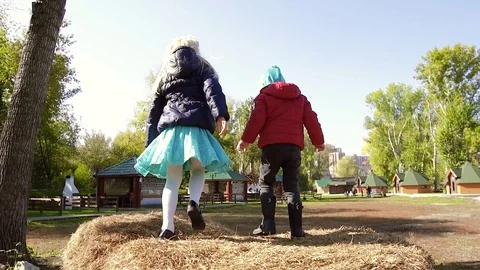 Two charming girls play in the fall in the street on a haystack Stock-Footage 70824943