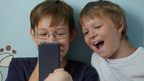 Two cheerful boys using smartphone indoors, Close-up Stock-Footage 94379492