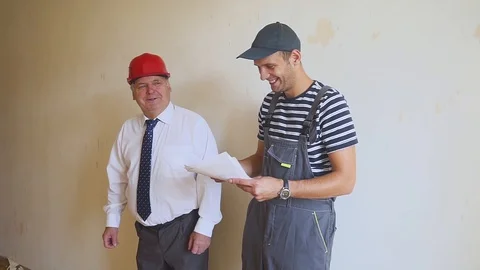 Two cheerful builders are discussing the construction plan and laughing. Senior Stock Footage 95324778