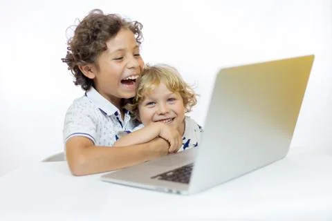Two cheerful children 4 and 9 years old, using a computer sitting at a desk Stock Photos