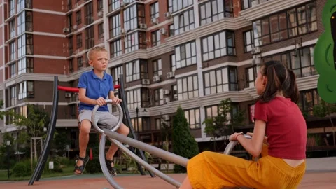 Two cheerful children are riding on a swing on the playground in the courtyard. Stock Footage 204834904