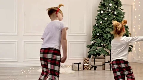 Two Cheerful Children are Running Around the Living Room in Their Pajamas Near Stock Footage 230108985