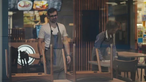 Two cheerful divers waiters cleaning cafe before workday in the morning Stock Footage 123438525