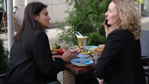 Two cheerful female managers discuss their work matters over business lunch Stock Footage 139685424