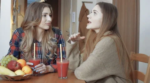 Two cheerful girls drinking fruit cocktail and gossiping. Stock Footage 62767523