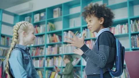 Two cheerful students talking in school library Video stock 108749727