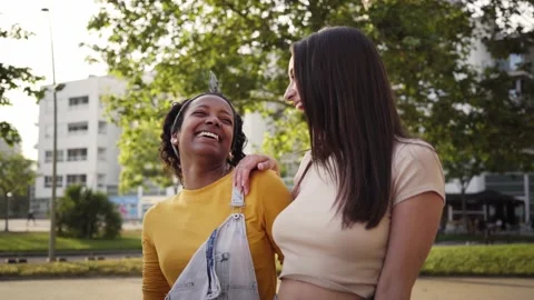 Two cheerful stylish and friendly Caucasian and African American girls walking Stock Footage 234015941