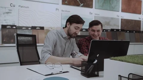 Two cheerful successful young men discussing business project in the design Stock Footage 84731700