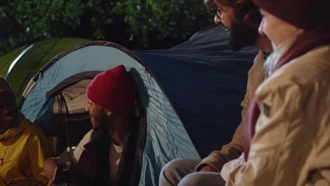 Two cheerful young adults couples enjoying romantic winter evening camping Stock Footage 252084891