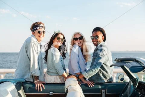 Two cheerful young couples standing near cabriolet Stock Photos