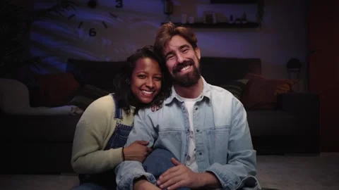 Two cheerful young in love looking at smiling camera in living room Video stock 255668388