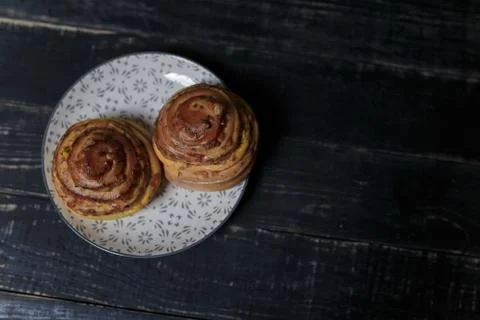 Two cheese and dill bread buns on plate standing on black wooden background. Stock Photos