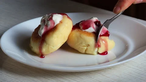 Two cheesecakes on a plate with sour cream and jam. Stock Footage 229889052