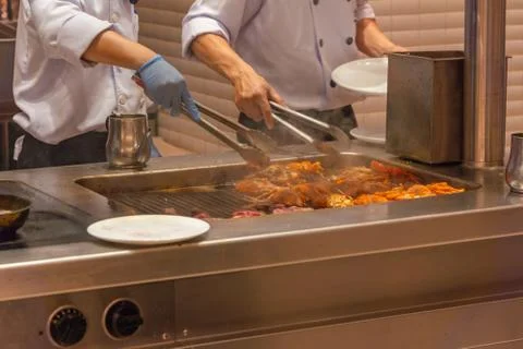 Two chef preparing grilled lobsters on electric stove in kitchen Foto stock