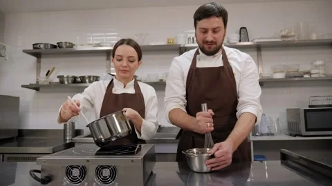 Two chefs cook strawberry jam together in a pot in a professional kitchen. Stock Footage 269492357