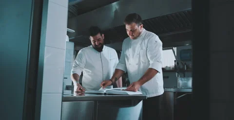 Two chefs look together at a book Stock Footage 204973260