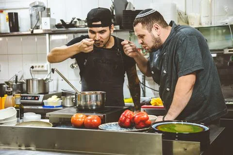 Two chefs in the restaurant kitchen are trying food. training Stock Photos