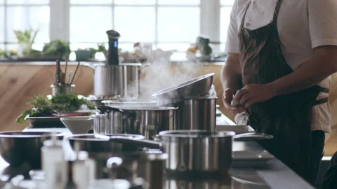 Two chefs talking by their work stations and counter with pots and pans in inter Stock Footage 199457586