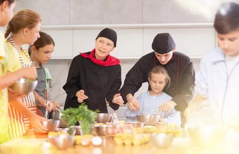 Two chefs teach children how to cook food - they beat eggs with whisk Stock Photos