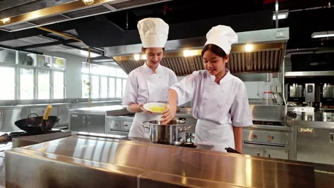Two chefs in white uniforms and hats collaborate while cooking on a stove i.. Stock Footage 327122875