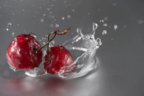 Two cherries fall into the water Stock Photos