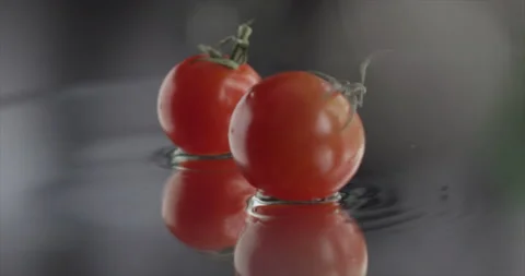 Two cherry tomato spinning on a mirror surface Stock Footage 200868847