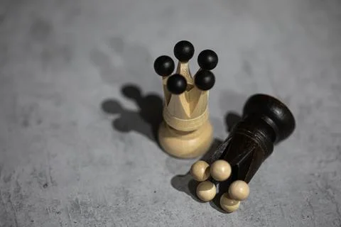 Two chess queens on gray table White piece stands black piece lies. Win and lose Stock Photos