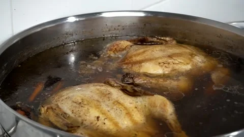 Two chicken carcasses are boiled in a large saucepan with spices Stock Footage 247733880
