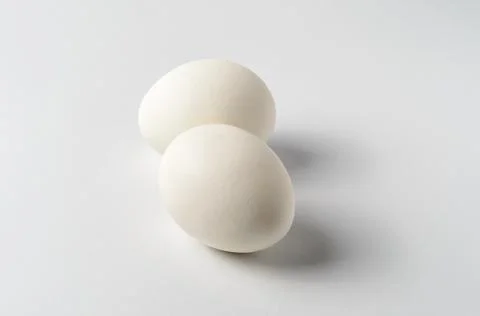 Two chicken eggs cool boiled on a white background Stock Photos