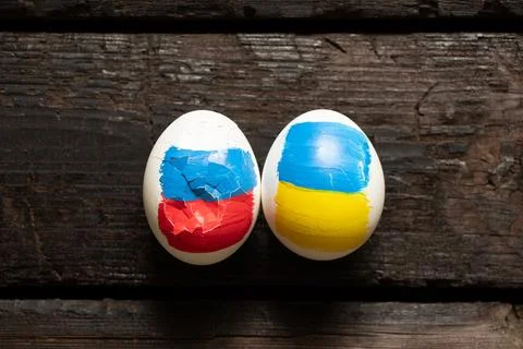 Two chicken eggs, one with the flag of Russia is broken and the second with.. Stock Photos