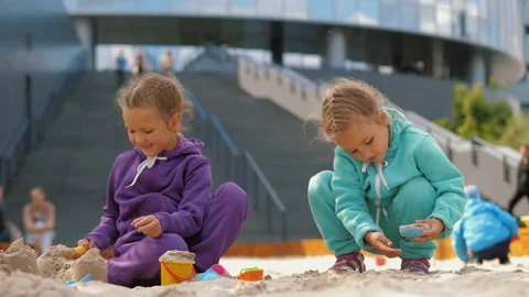 Two children 4-5 years old sitting in sandbox, playing with toys and buckets Stock Footage 138416783
