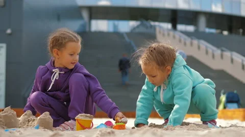 Two children 4-5 years old sitting in sandbox, playing with toys and buckets Video stock 141118366