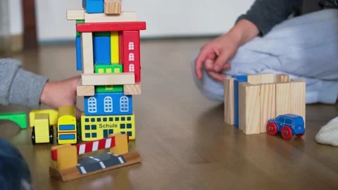 Two children 7-9 years old, boys plays with colored wooden cubes, builds hous Video stock 163549678