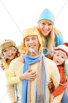 Two children and wife in winter clothes embracing a happy man Stock Photos