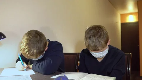 Two children are doing homework at the table. Protective masks during a pandemic Stock Footage 130661458