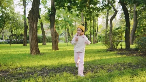 Two children are joyfully running across a vibrant park with lush green grass Stock Footage 313750829