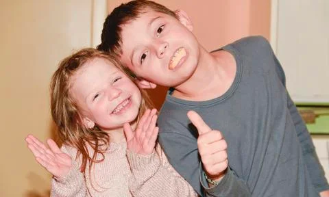 Two children are making faces. Boy is giving thumb up and girl is clapping the Фото