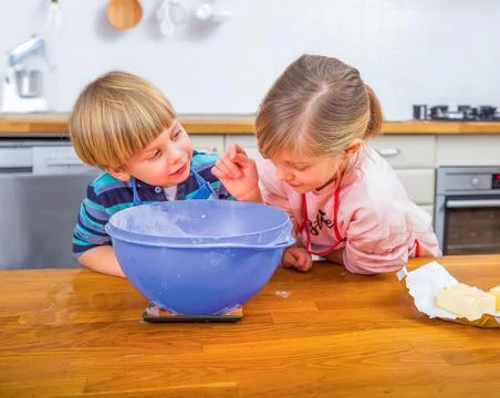 Two Children Baking Together in a Bright Modern Kitchen Environment Stock Photos